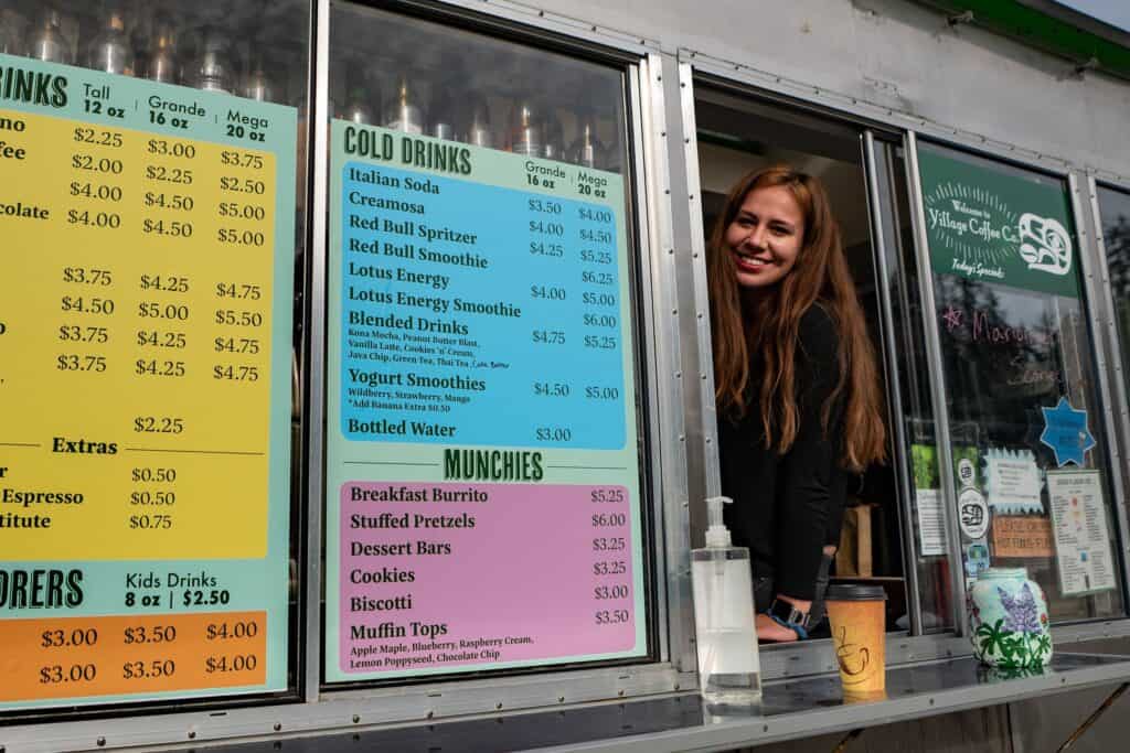 A woman smiles at the window of a food truck.