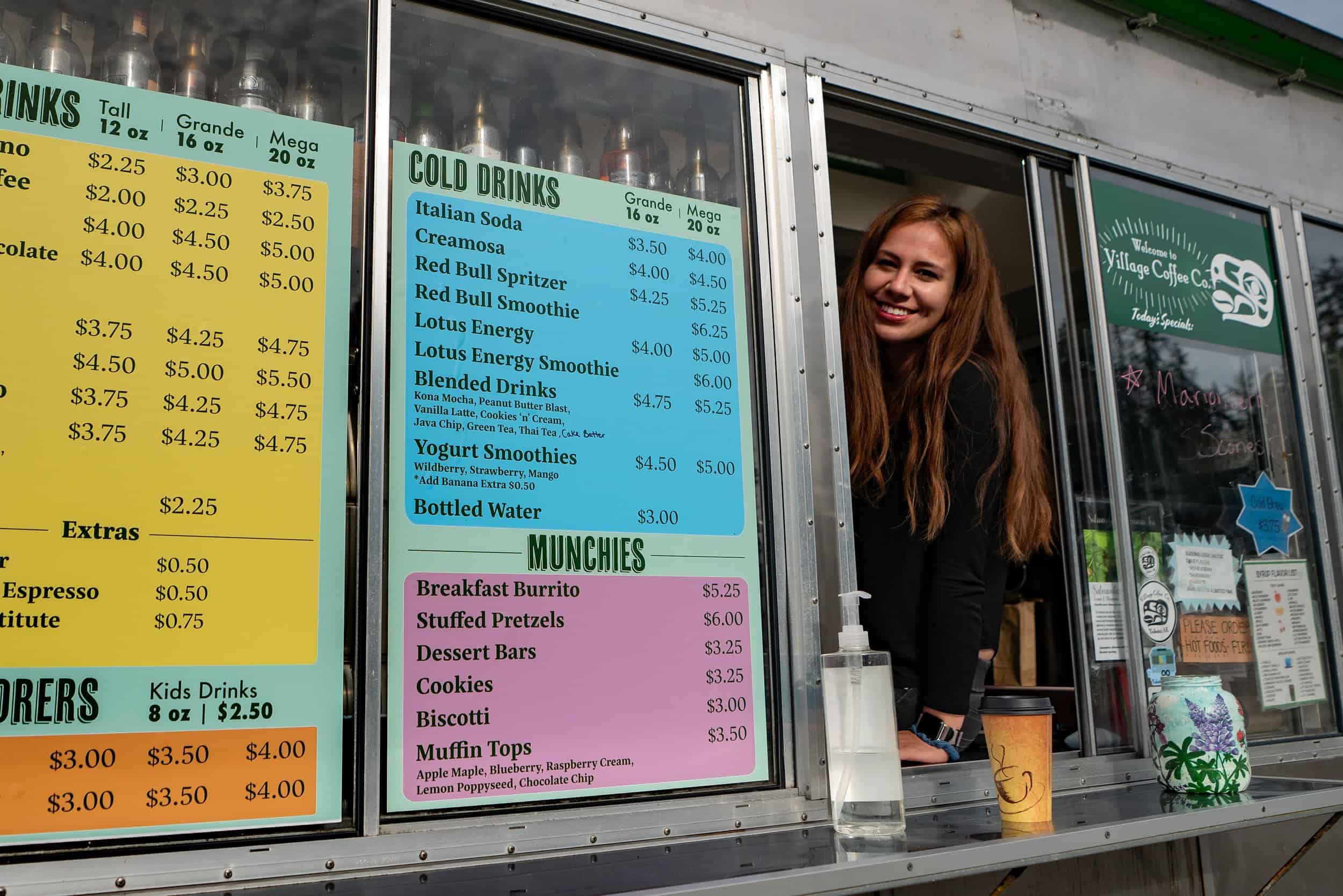 A woman smiles at the window of a food truck.
