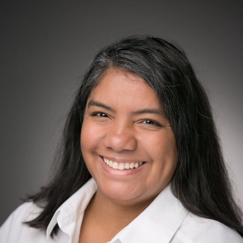 A woman with long black hair and a white shirt.