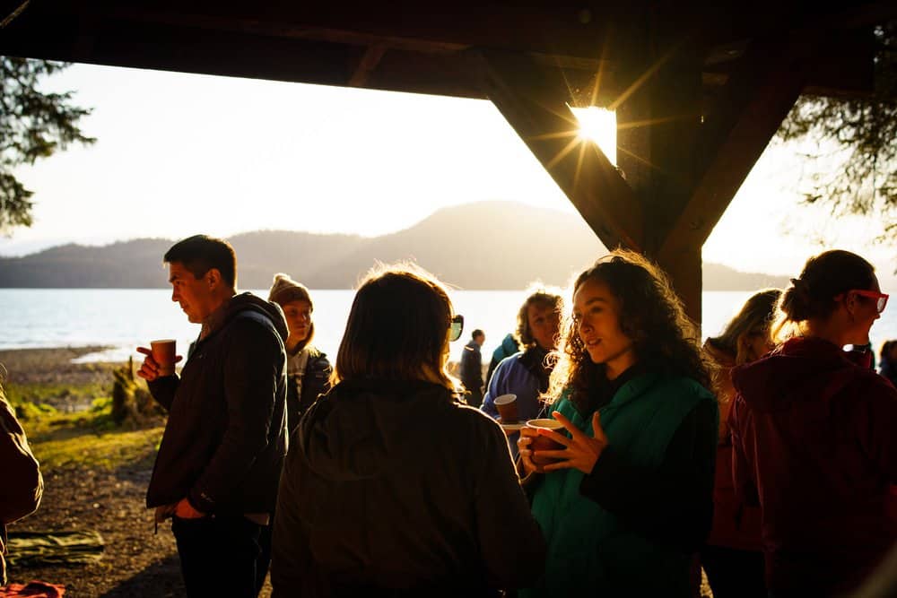 People standing around a table at sunset with the sun shining.