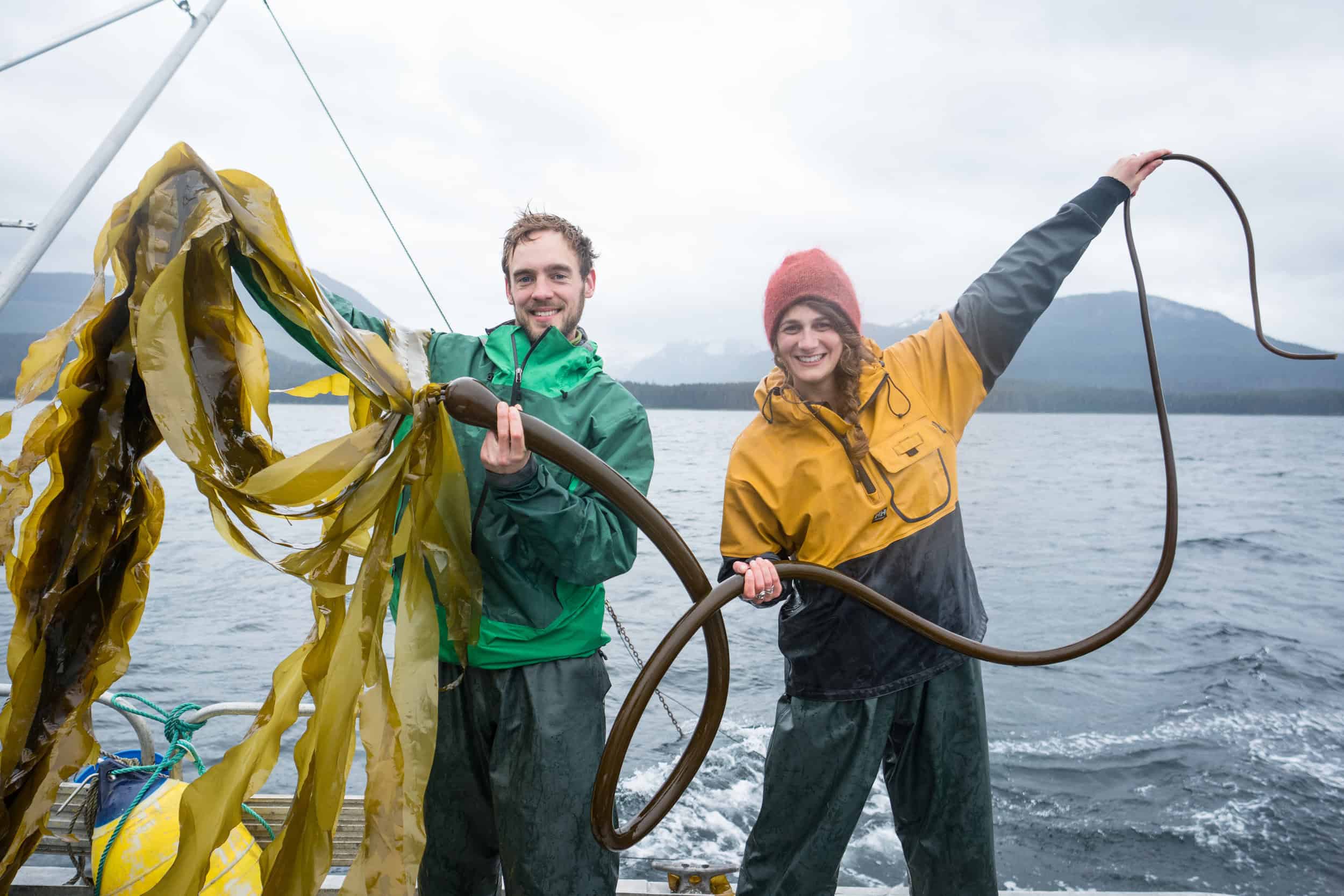 From the capital city of Juneau, Matt and Lia are serving up delicious food flavored from the sea. They are shown here holding up kelp with a backdrop of oceans and mountains.