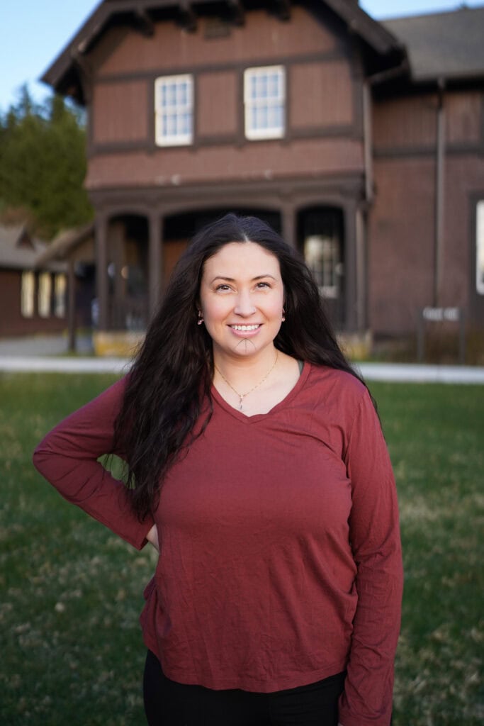 A woman in a red shirt standing in front of a building.