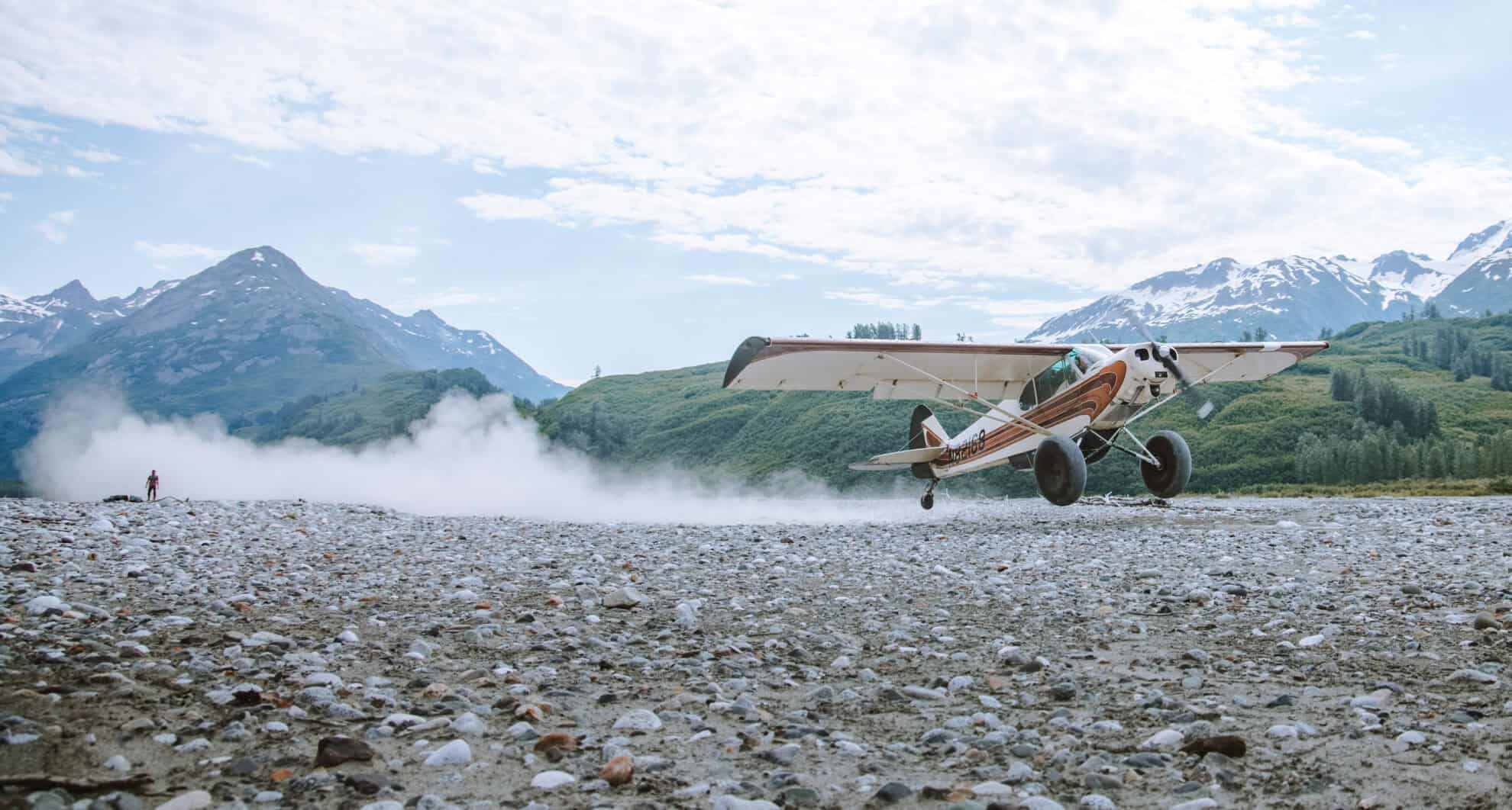 A small airplane taking off from a gravel road.
