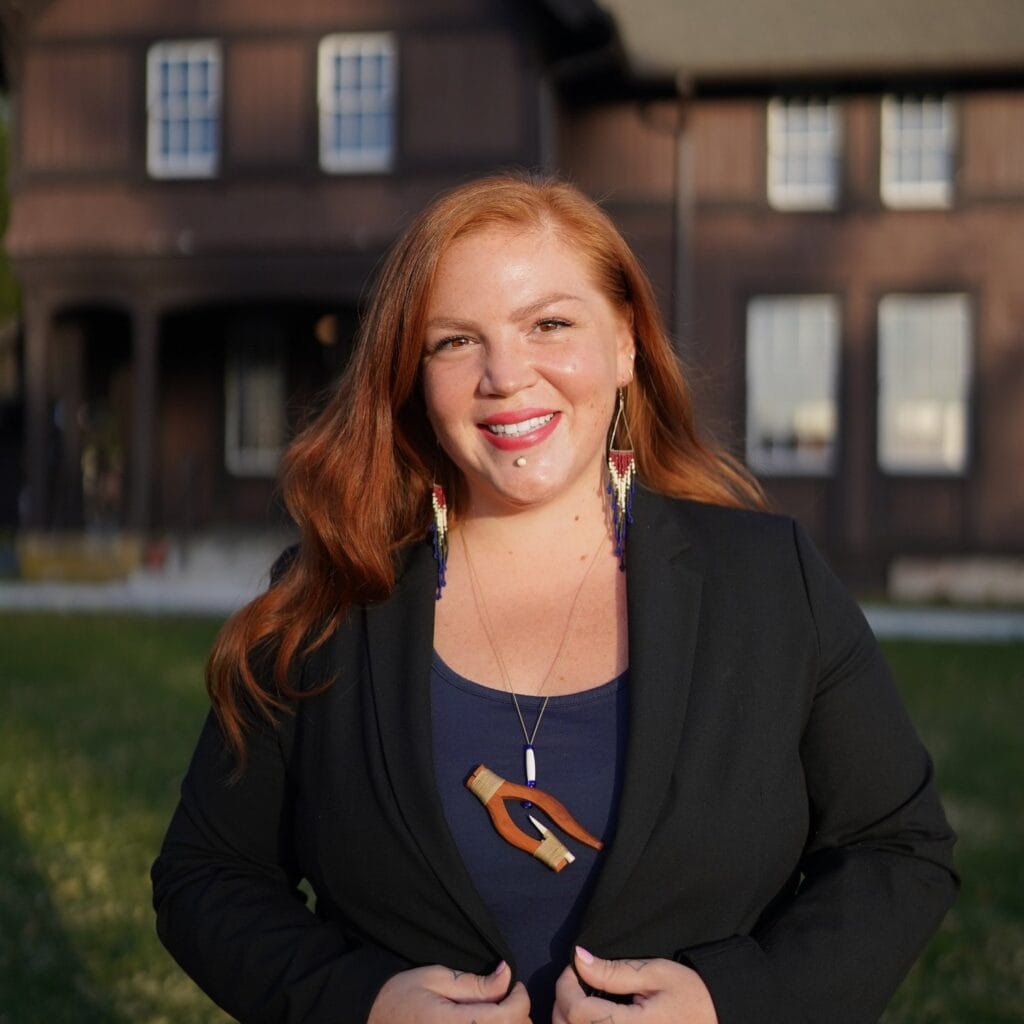 A woman with red hair standing in front of a house.