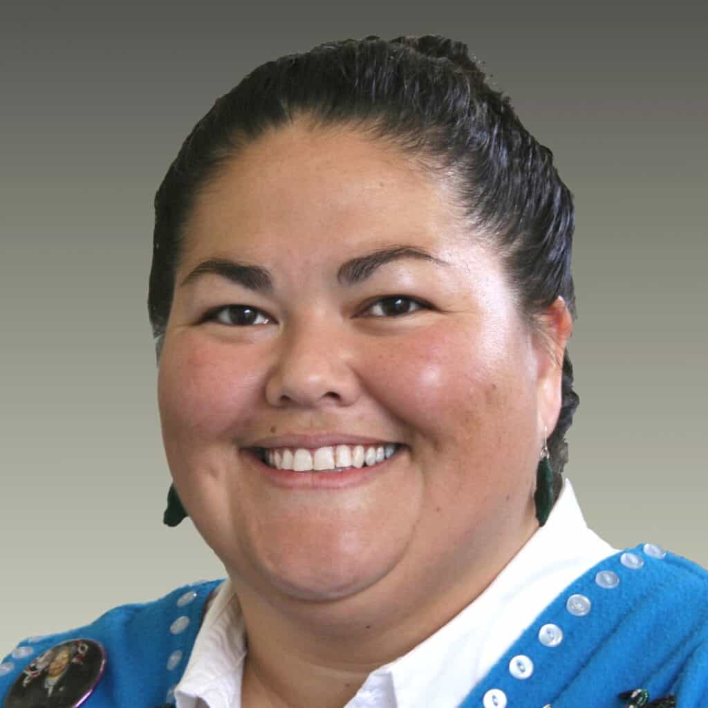 A headshot of La Quen Náay against a grey background.
