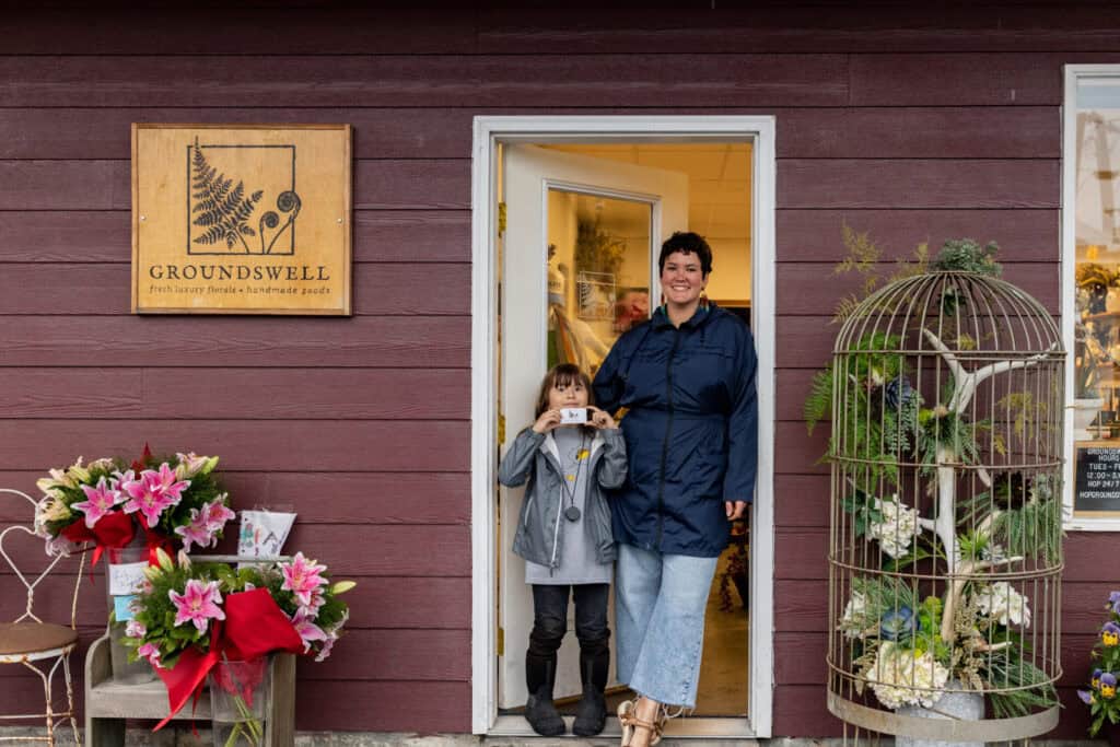 A woman and child standing in front of a flower shop.
