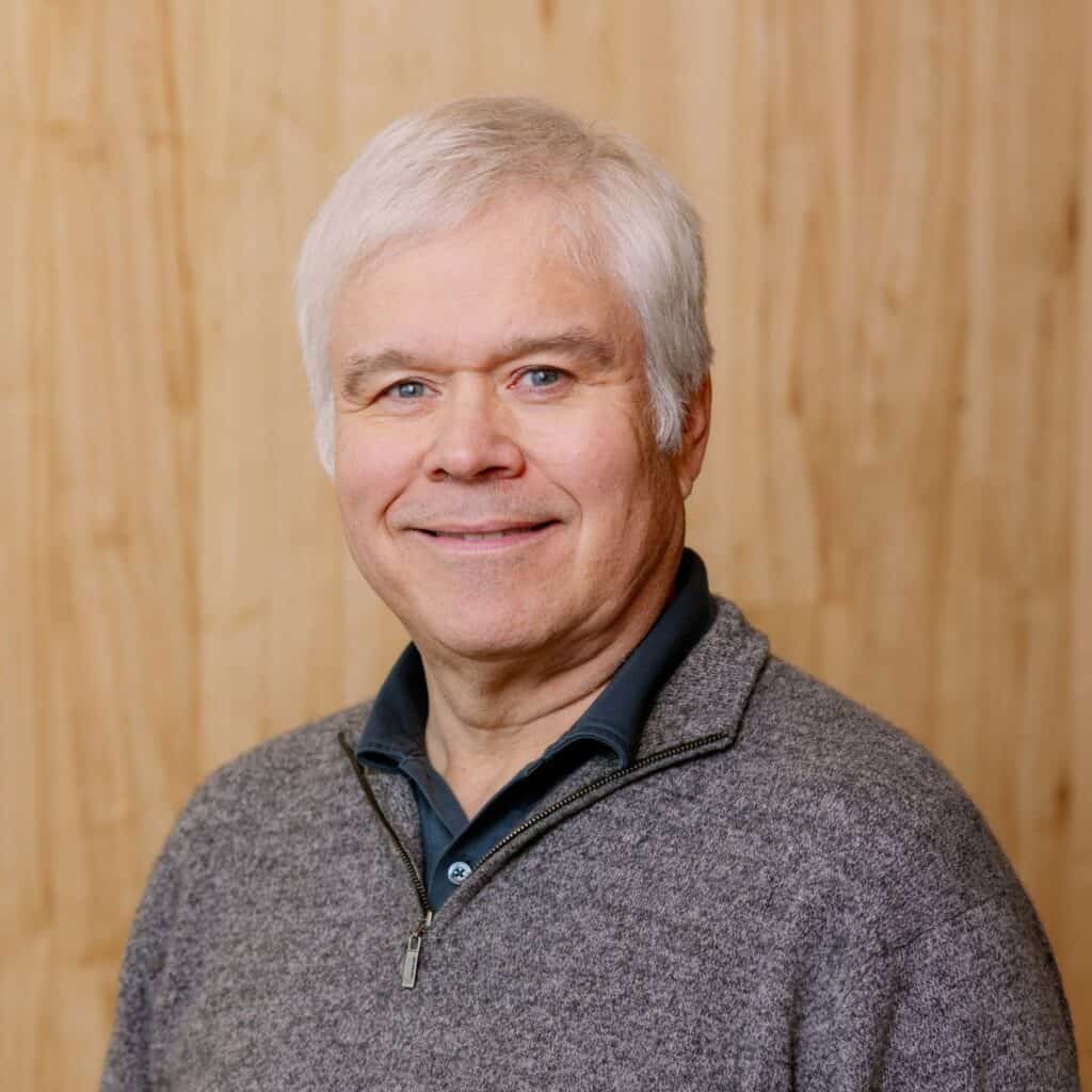 A headshot of Robert Allen against a wood paneled background.