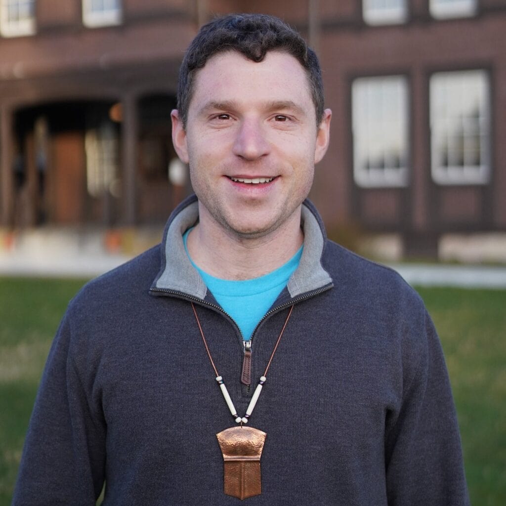 A man wearing a necklace in front of a building.