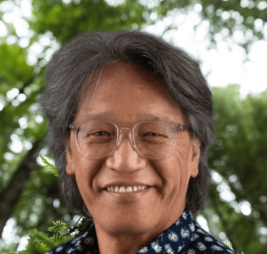 A smiling man with glasses and a blue shirt.