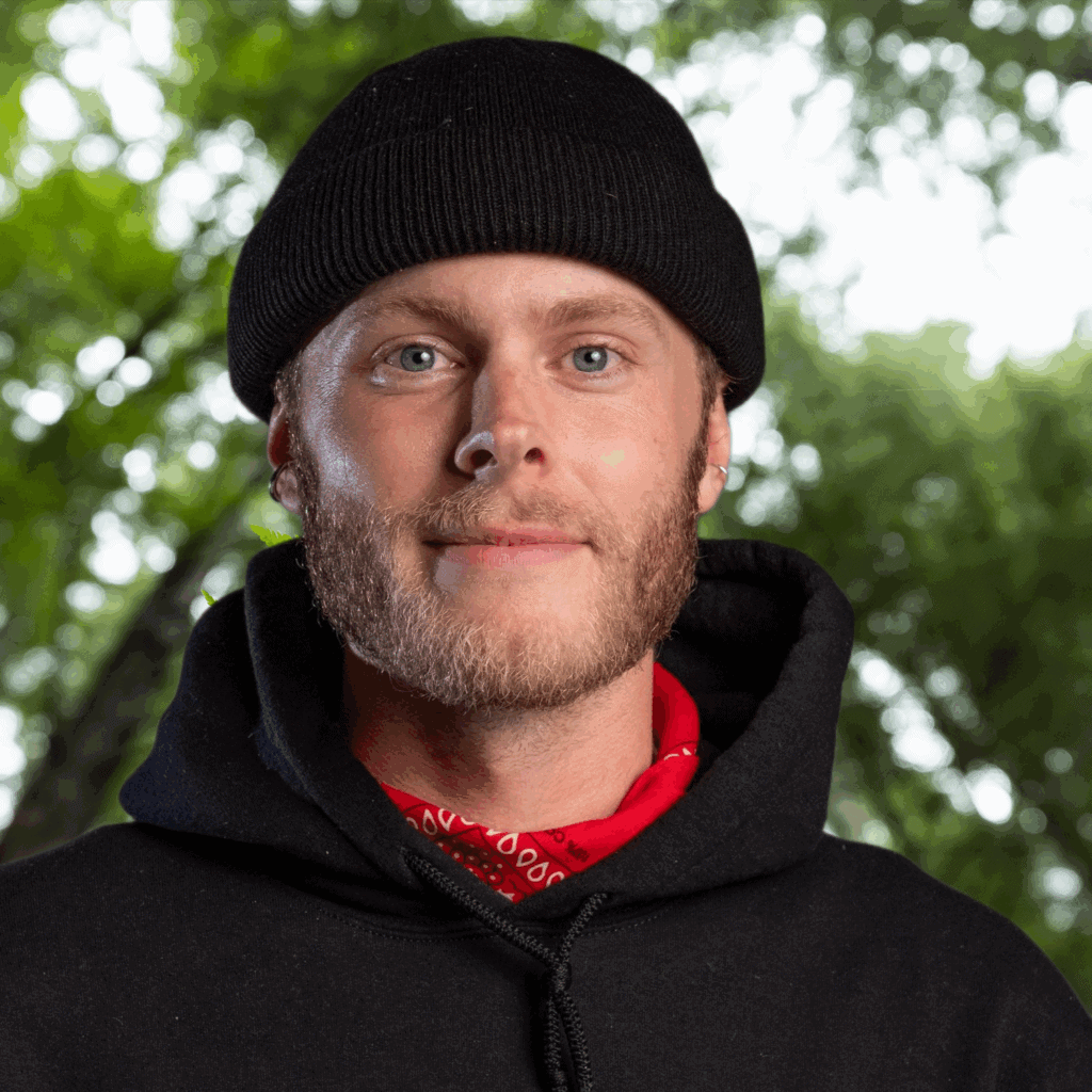 A man wearing a black hoodie and red bandana.