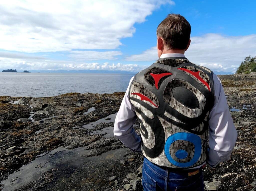 A man wearing a vest in front of the ocean.