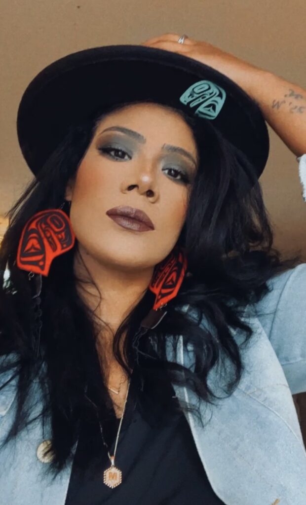 A woman with tattoos and a hat is posing.