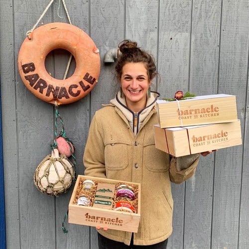 A woman holding a box of food and a life preserver.