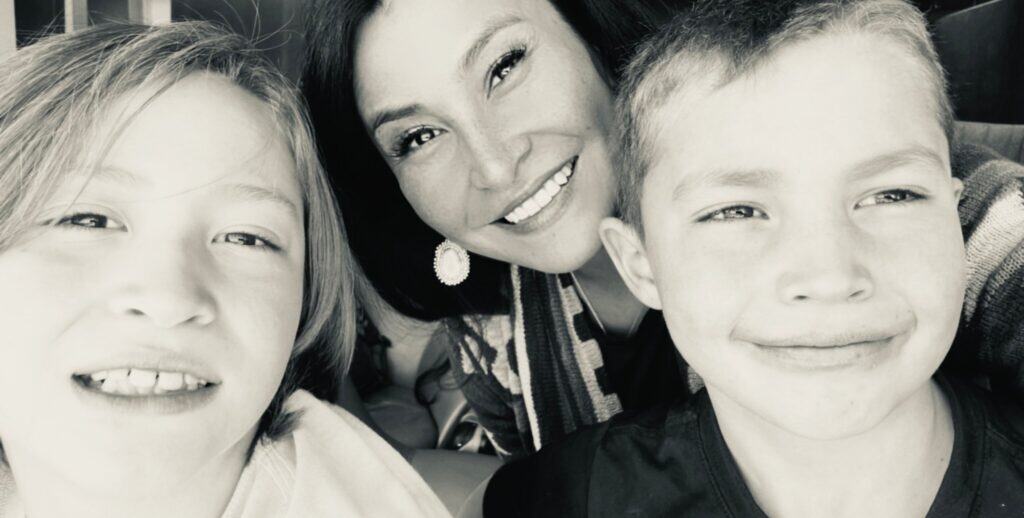 A woman and two boys are smiling for the camera.