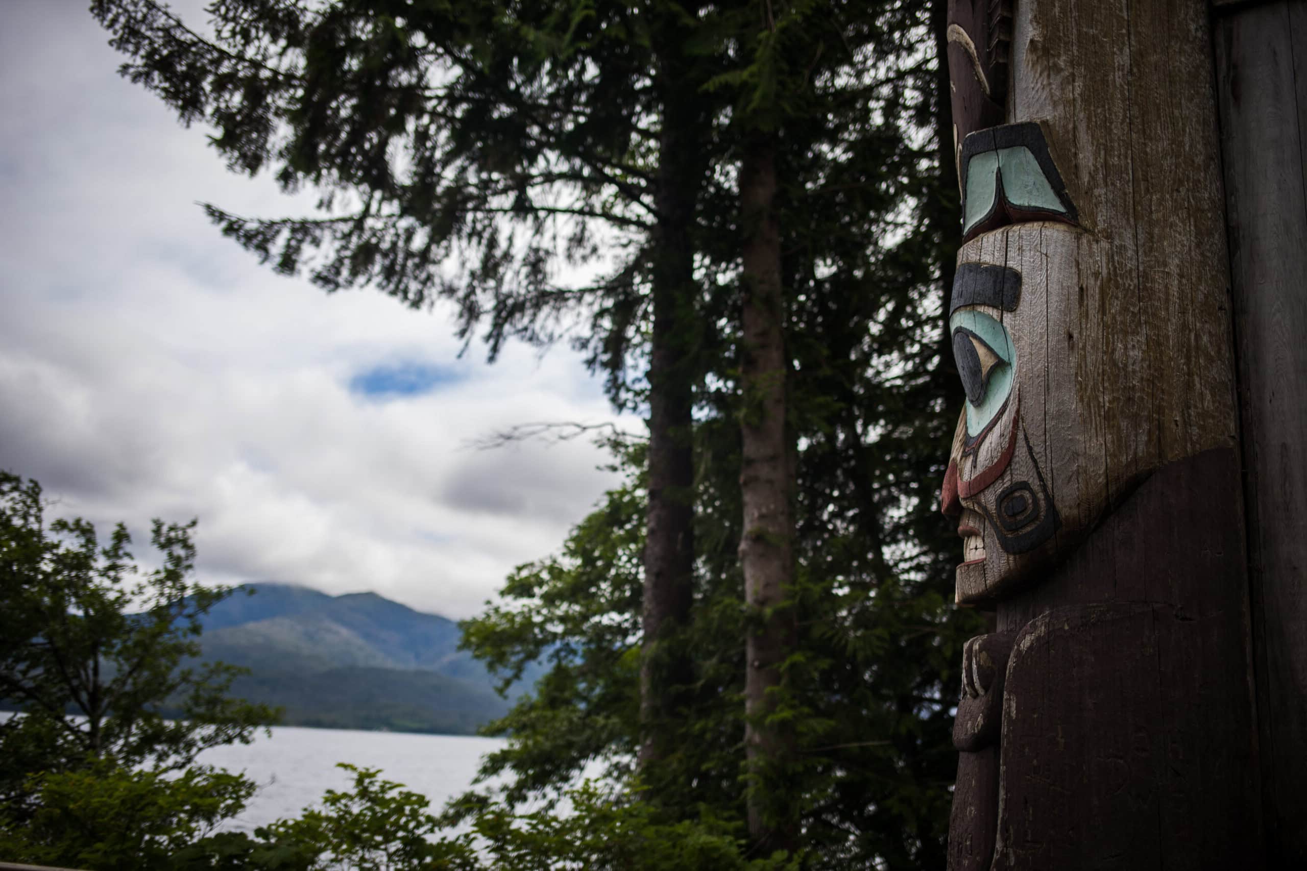 A totem pole with a mountain in the background.
