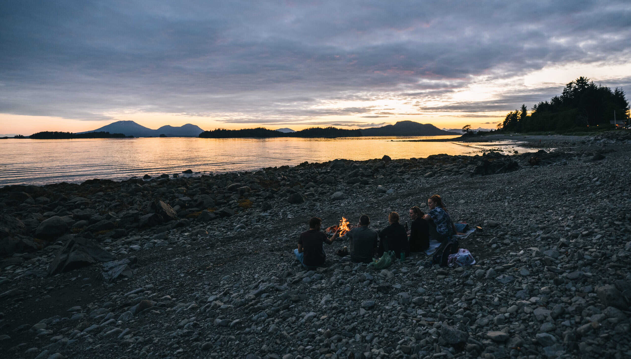 People sitting on the beach with a fire.