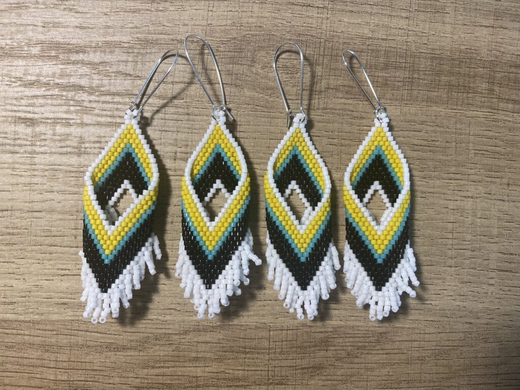 Three beaded earrings with yellow, teal, black and white.