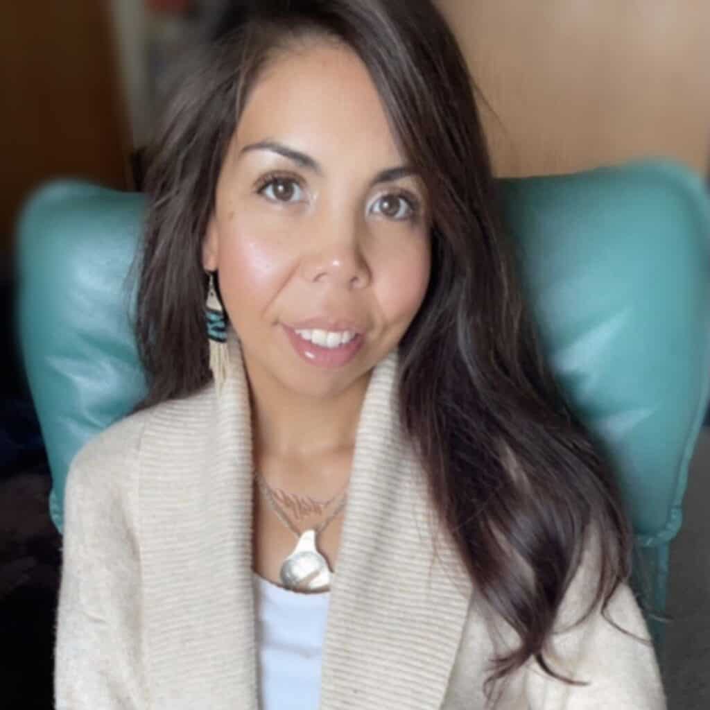 A woman with long brown hair and a white sweater.