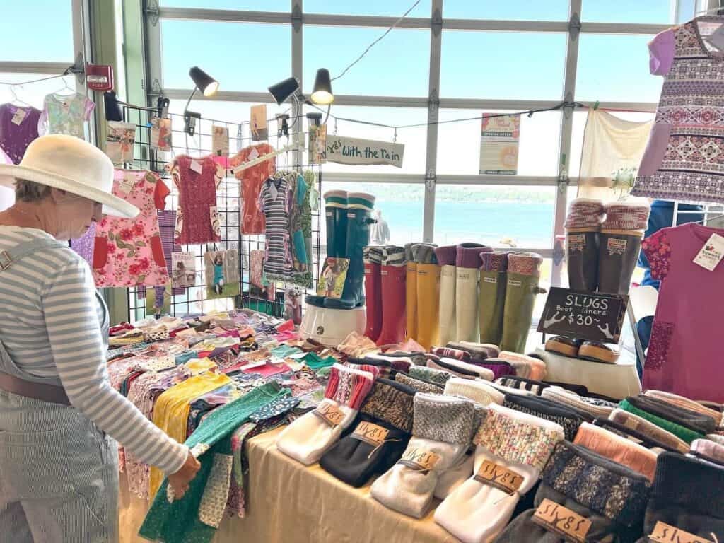 A woman is looking at a table with lots of items on it.