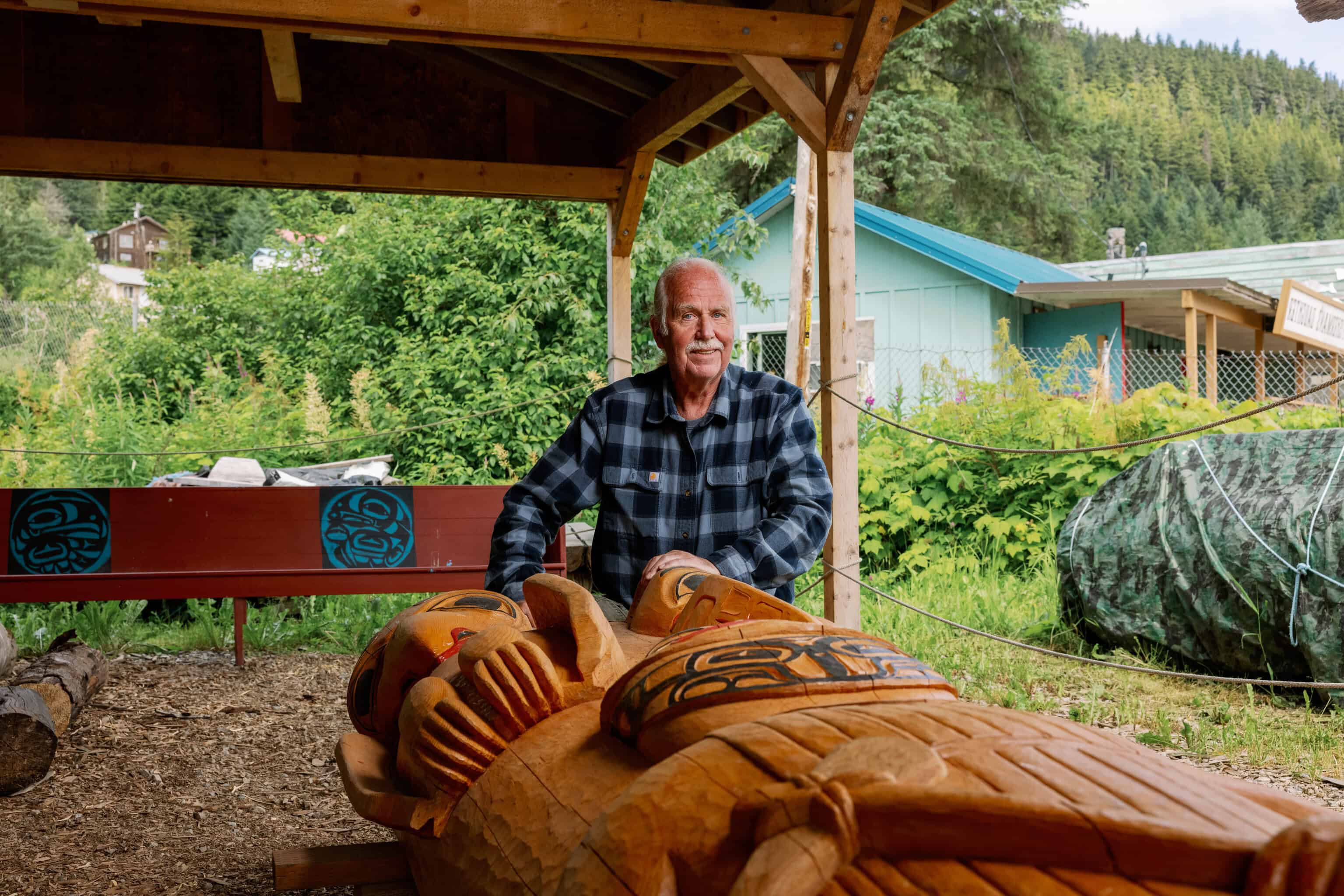 A man is standing next to a carved totem.