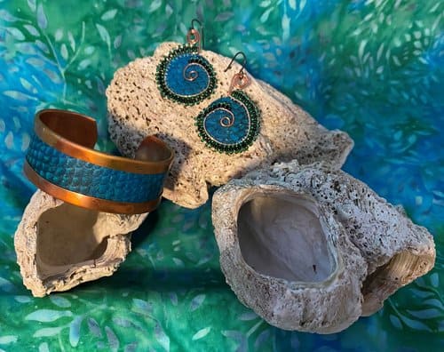 A pair of earrings and a bracelet sitting on a rock.