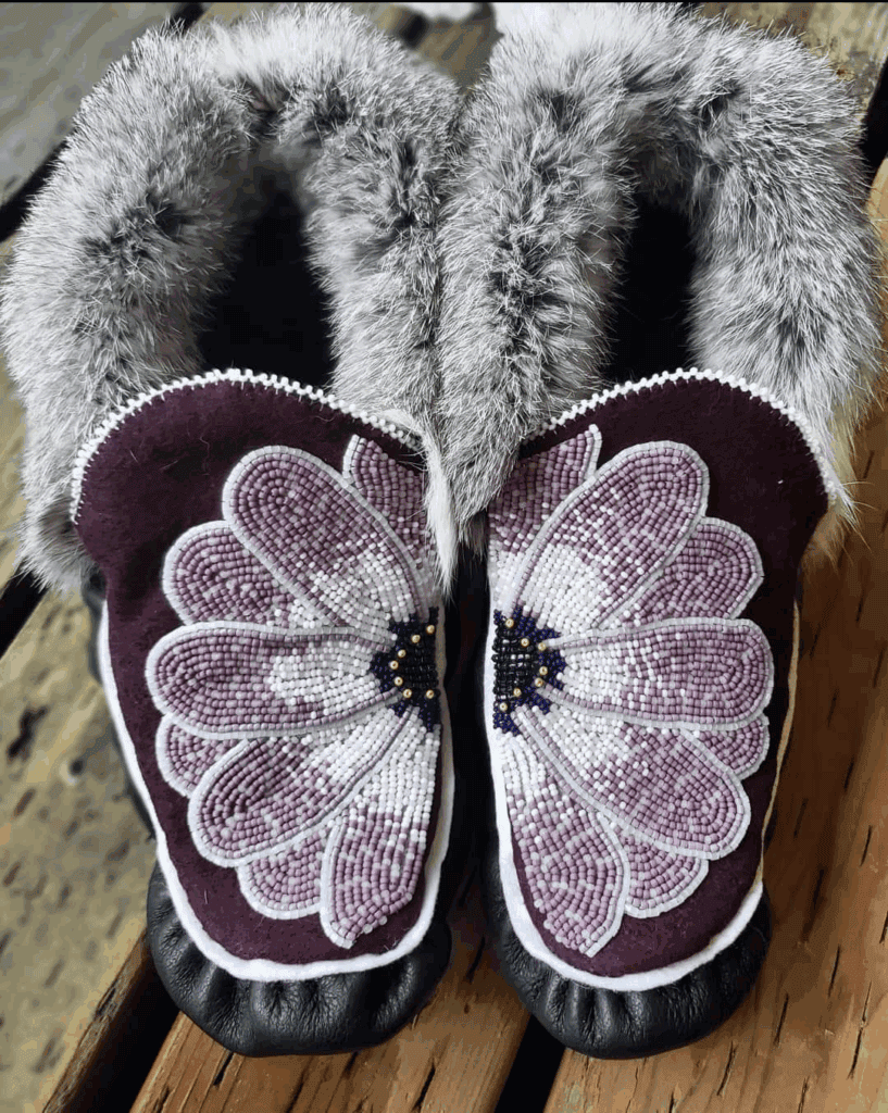 A pair of moccasins with a beaded flower on them.