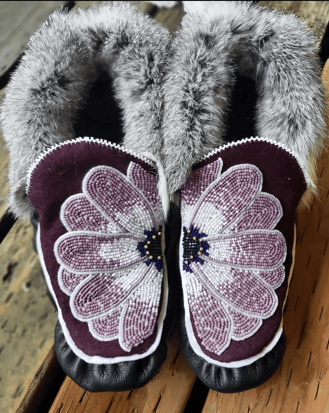 A pair of moccasins with a beaded flower on them.
