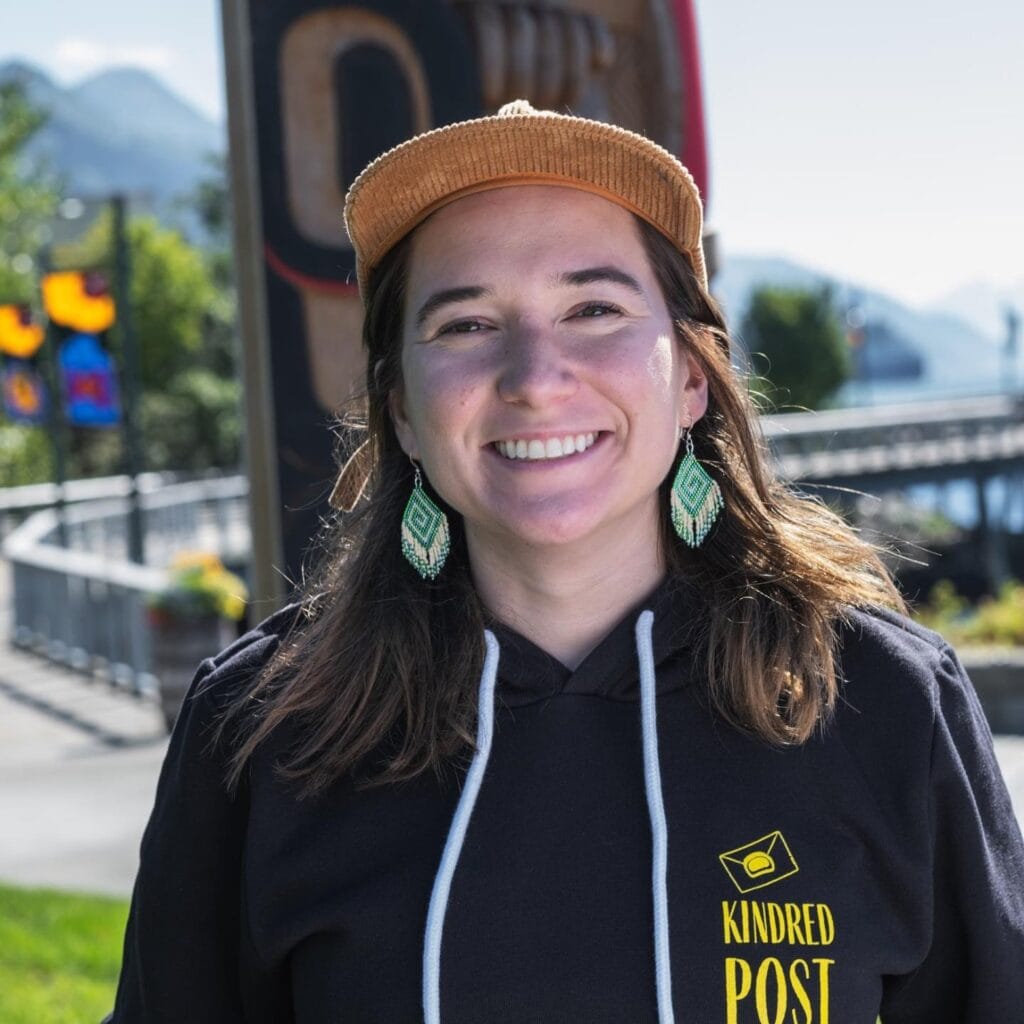 A woman wearing a black hoodie, beaded earrings, and a hat.