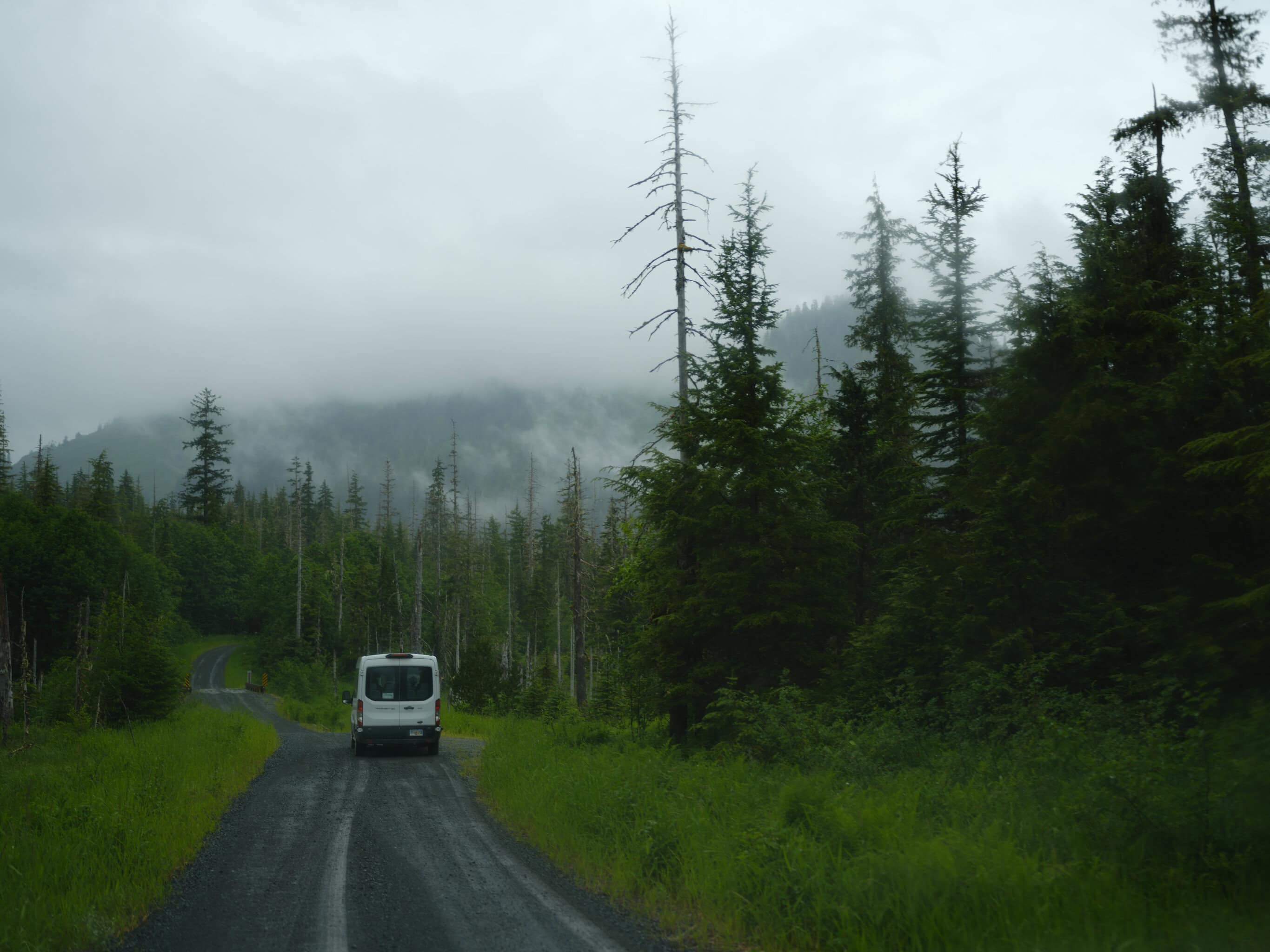 a van drives further into a remote and wild road.